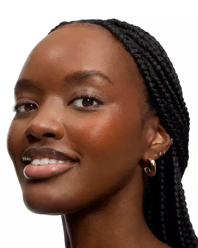 Mujer sonriente con trenzas largas y labios brillantes.