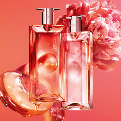 Dos frascos de perfume de Lancome con duraznos y una flor rosa.