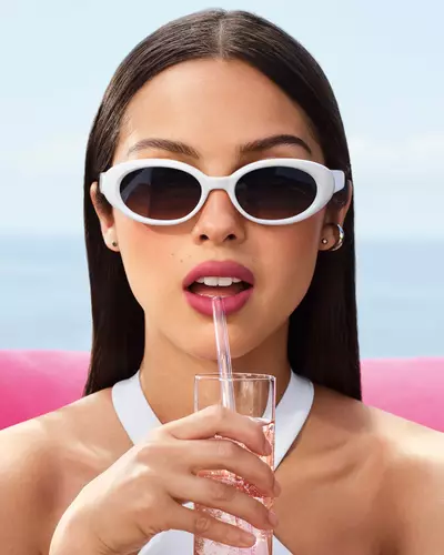 Olivia Rodrigo con anteojos de sol blancos y un look de labios en tono malva.